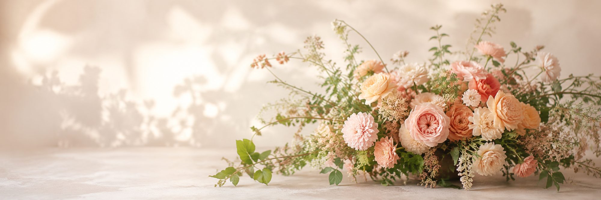 A soft, garden-style arrangement of blush and peach blooms with trailing greenery